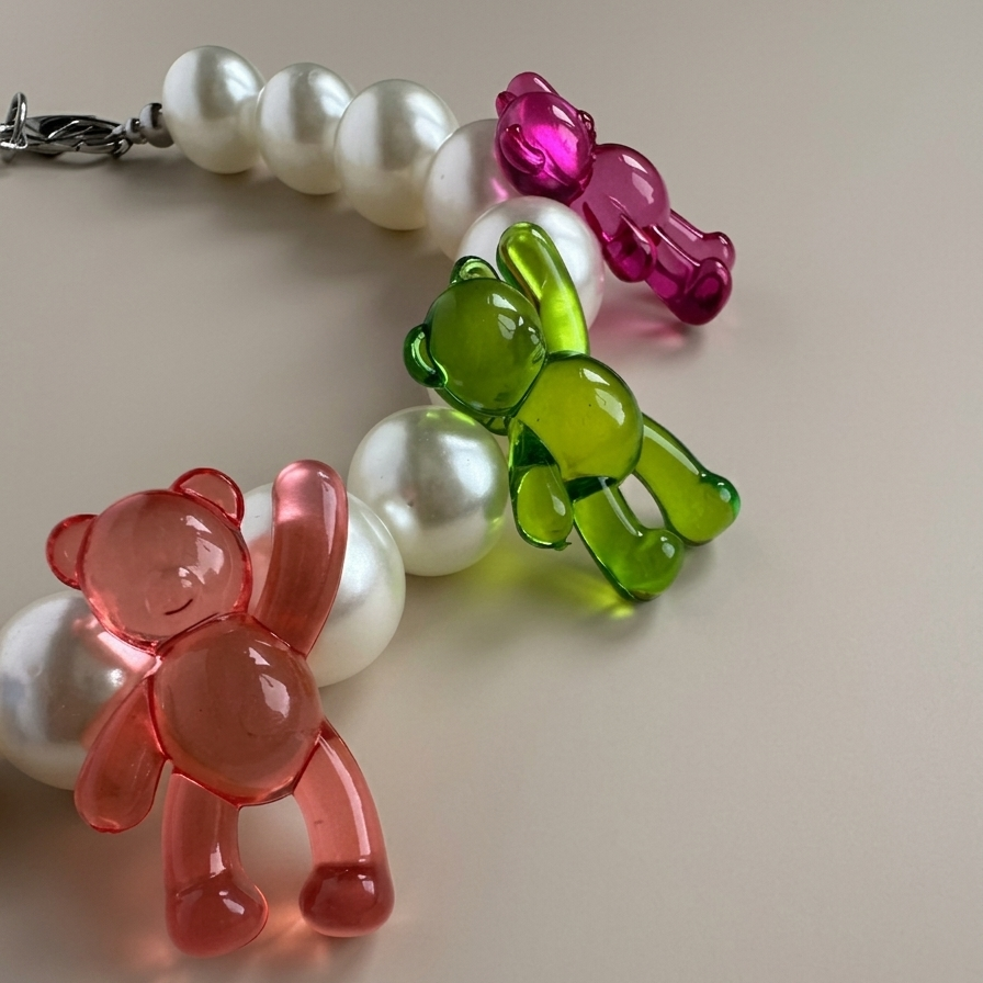 Necklace with white pearls and colorful bear-shaped charms on a light background