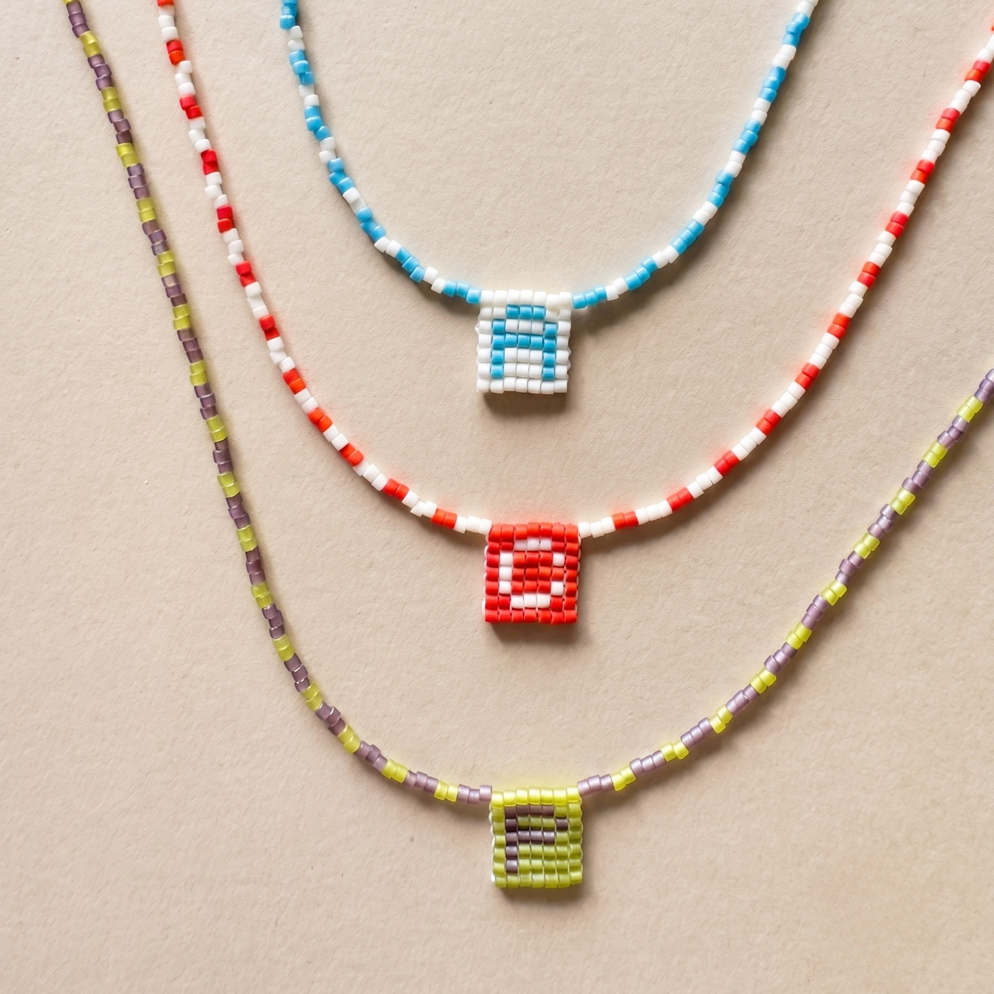 Handmade Miyuki beaded necklace forming a medal-style pendant with an initial letter