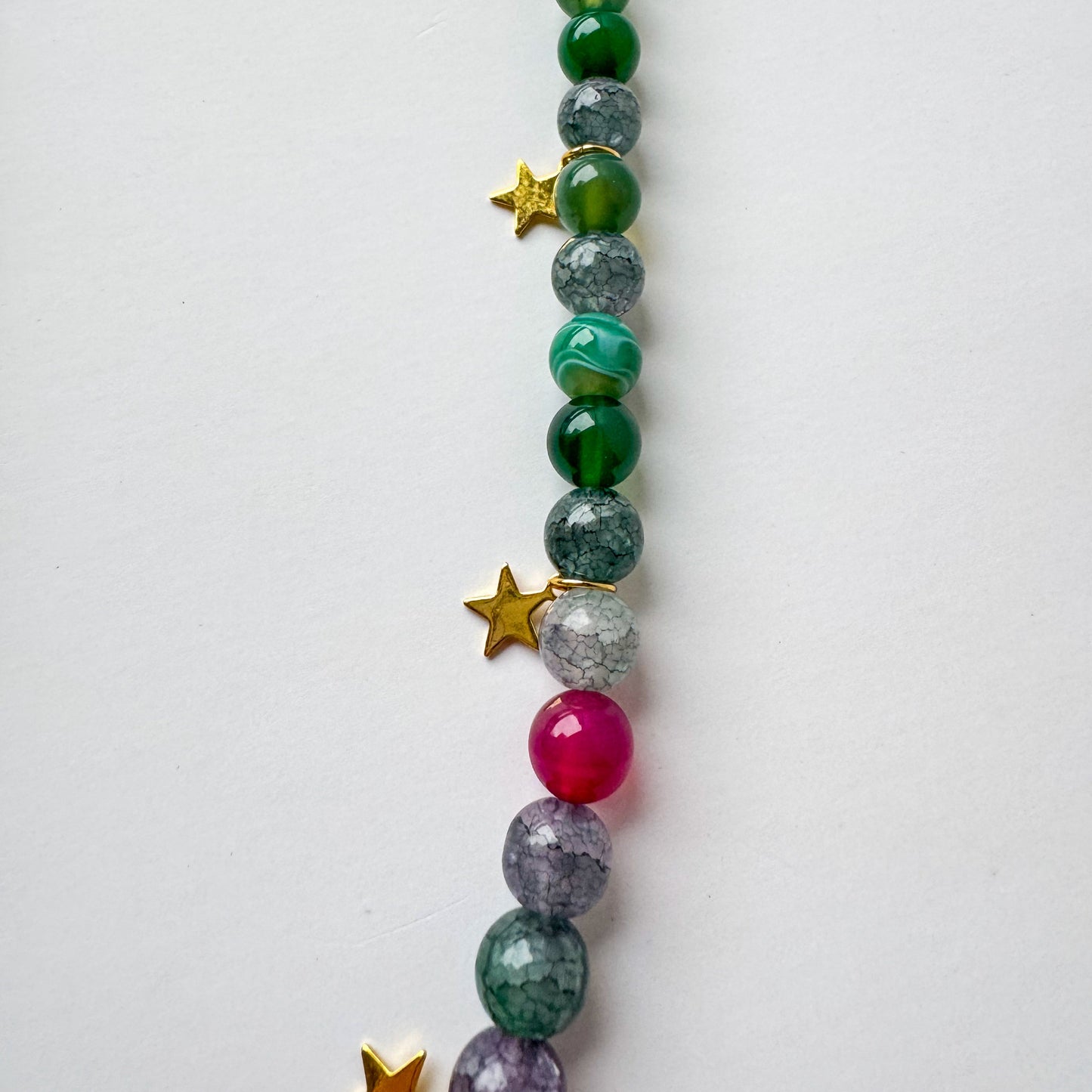 Long green beaded necklace with star accents, a silver carabiner clasp, and a small heart charm_details