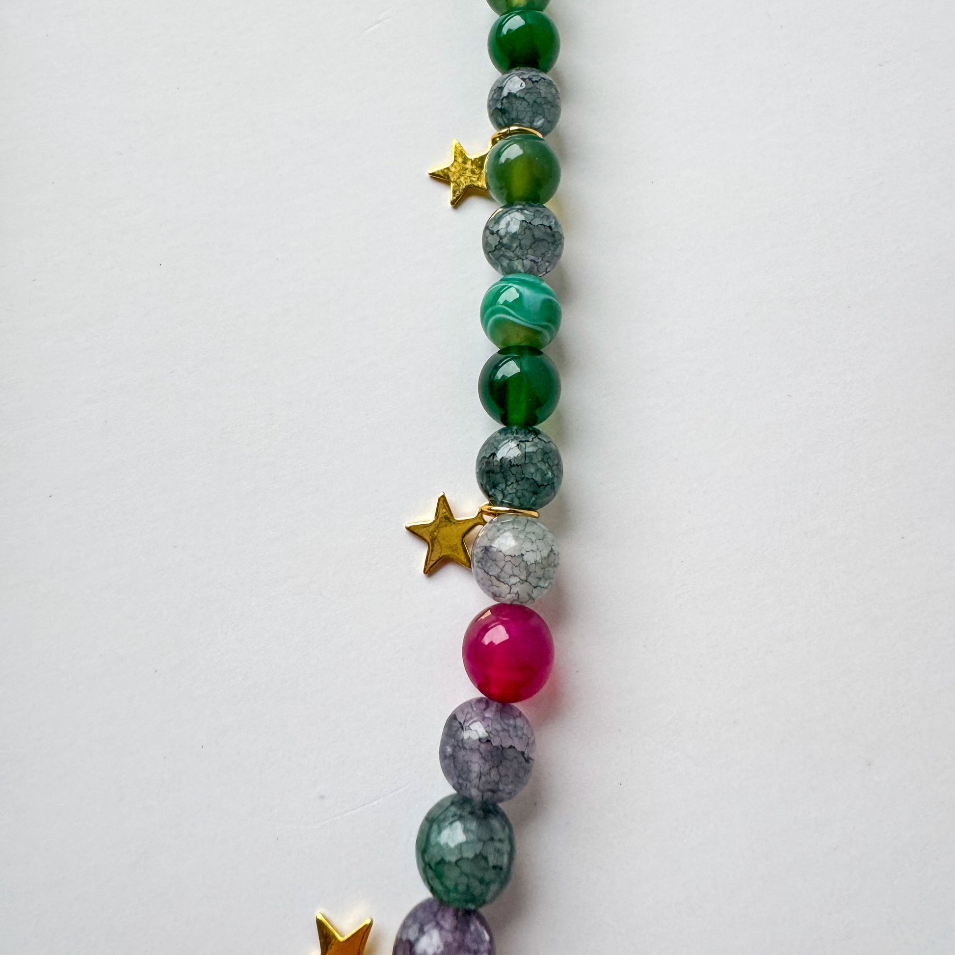 Long green beaded necklace with star accents, a silver carabiner clasp, and a small heart charm_details