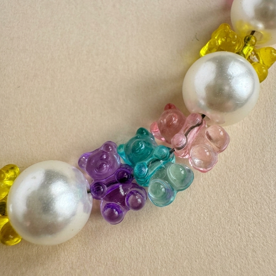 Necklace with pearls and colorful bear-shaped beads on a beige background