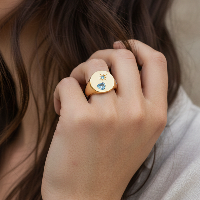 Close-up of a hand wearing a gold ring with a blue gemstone 