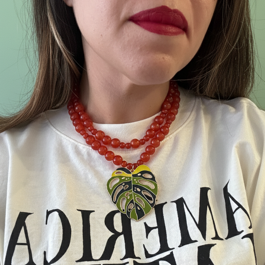 Layered two-strand necklace in warm red hues featuring a statement leaf pendant.