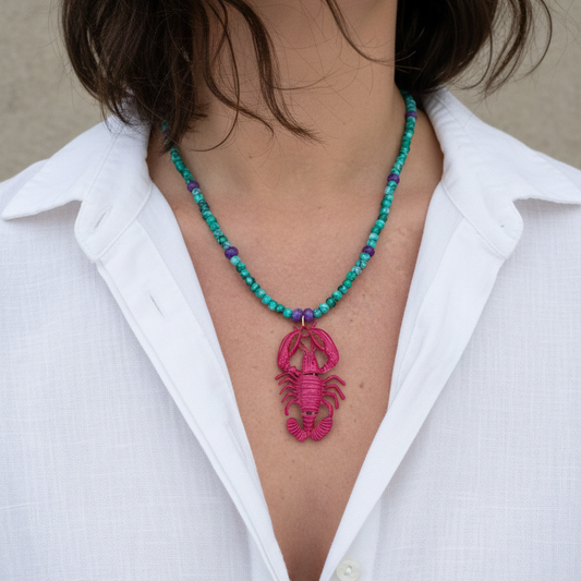 Handmade beaded necklace with green and purple beads and a pink lobster pendant_front