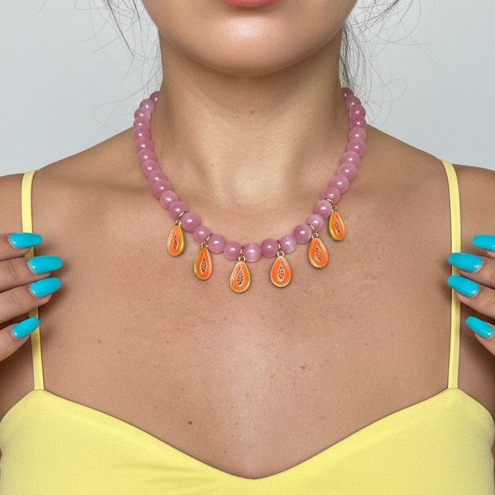 Statement pink beaded necklace featuring playful papaya pendants, perfect for a fun look.