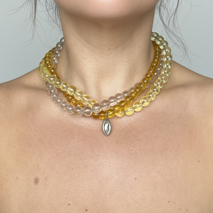 Three-strand beaded necklace in yellow and earthy tones featuring a Swarovski crystal pendant
