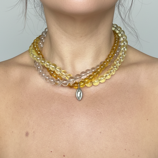 Three-strand beaded necklace in yellow and earthy tones featuring a Swarovski crystal pendant