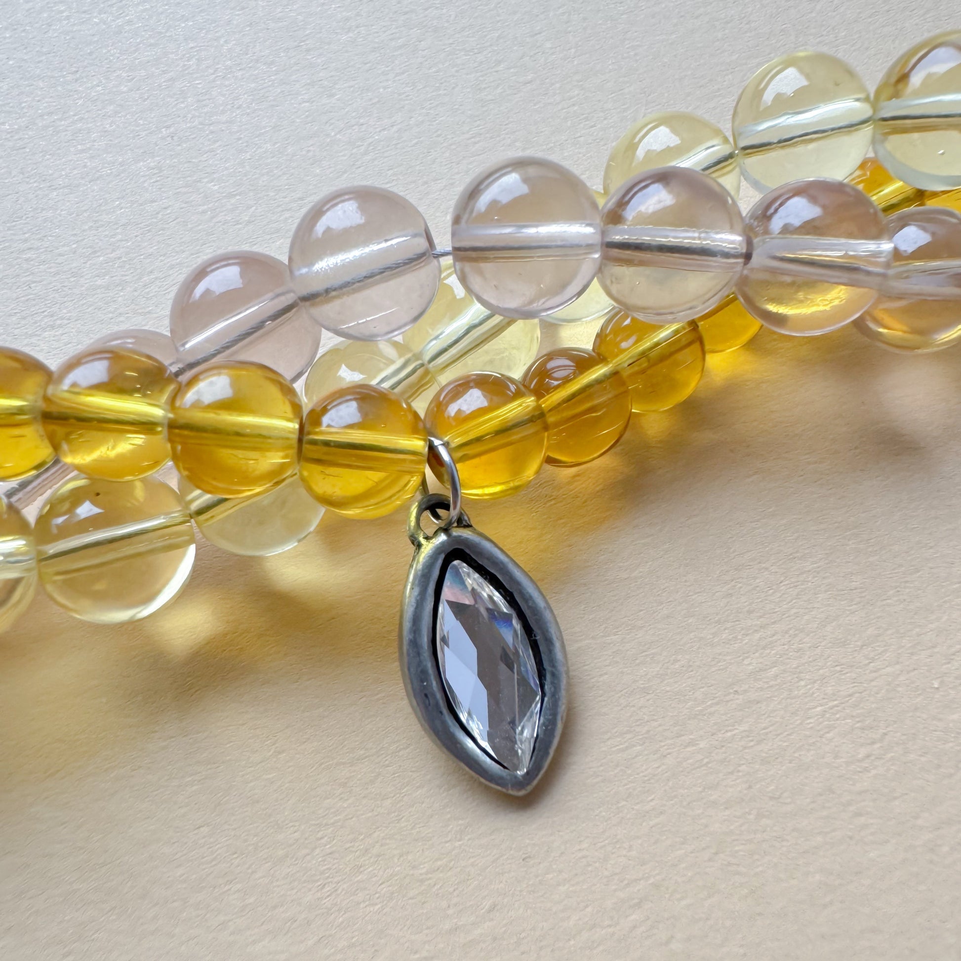 Three-strand beaded necklace in yellow and earthy tones featuring a Swarovski crystal pendant_detail